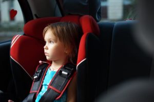 Child in auto baby seat in car looking at window